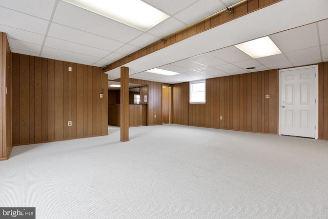 below grade area featuring a drop ceiling, carpet, and wooden walls