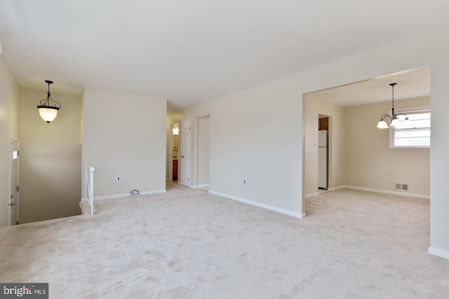 unfurnished living room featuring a chandelier, light colored carpet, visible vents, and baseboards