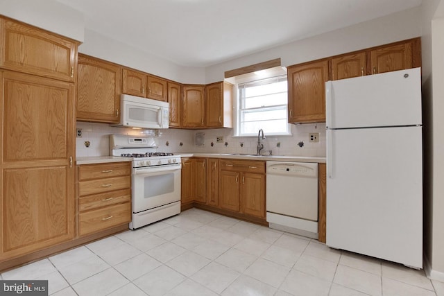 kitchen with tasteful backsplash, white appliances, light countertops, and a sink