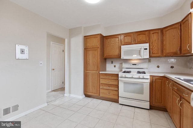 kitchen featuring tasteful backsplash, light countertops, visible vents, brown cabinetry, and white appliances