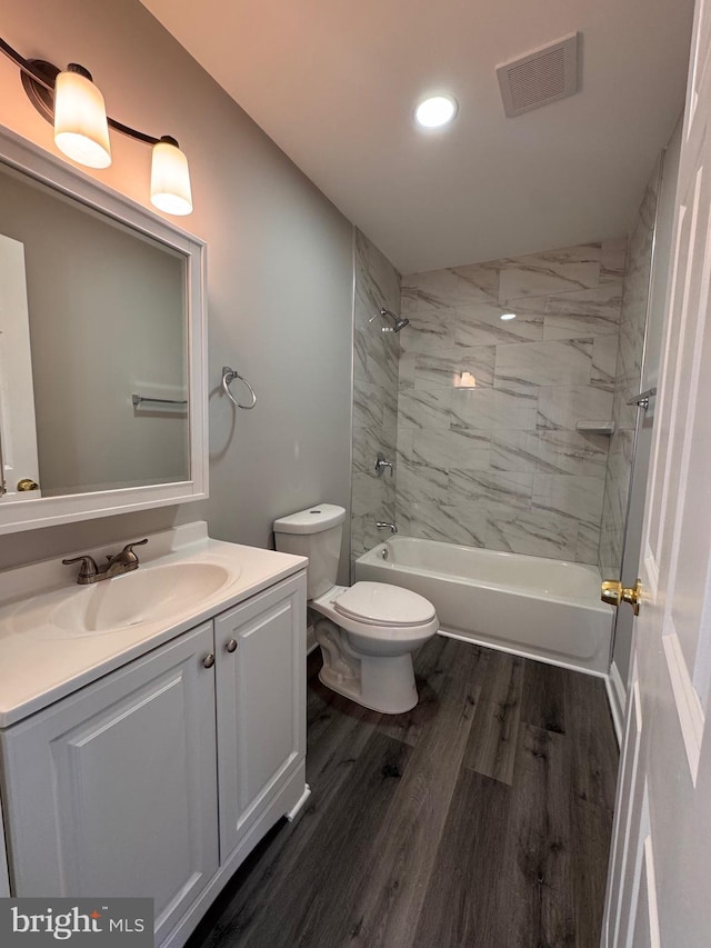 bathroom featuring visible vents, toilet, vanity, shower / tub combination, and wood finished floors