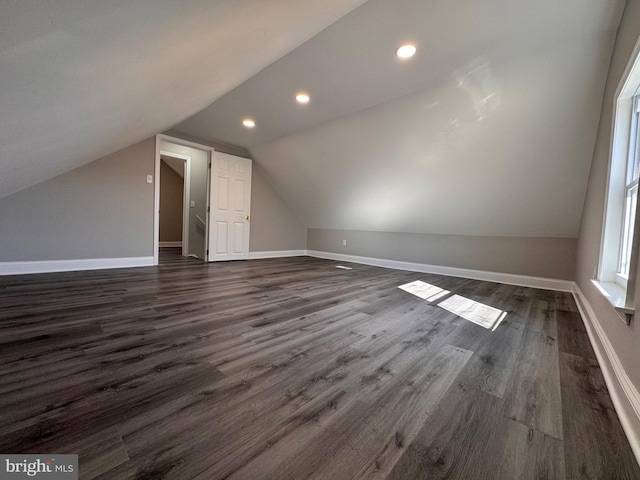 additional living space featuring baseboards, vaulted ceiling, dark wood-style flooring, and recessed lighting