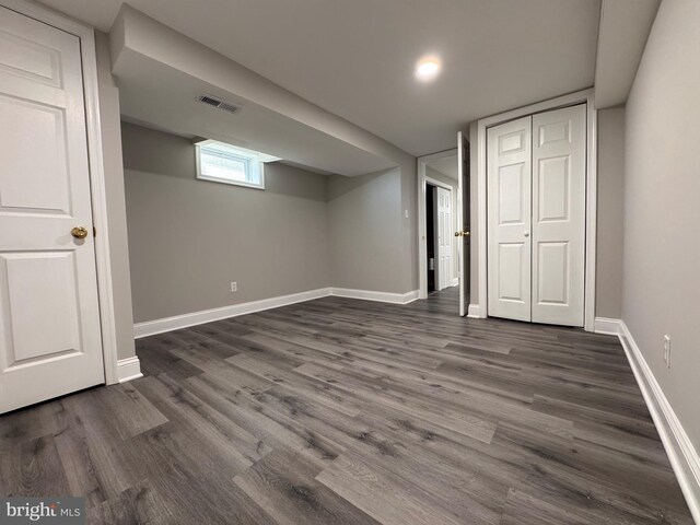 basement with dark wood-type flooring, visible vents, and baseboards