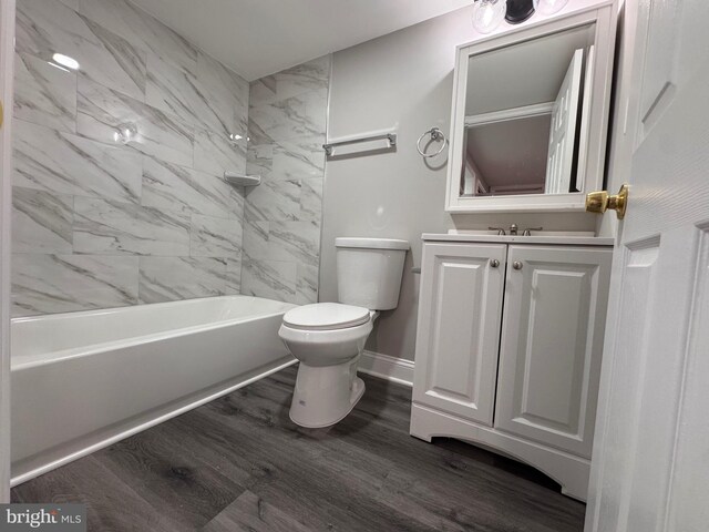 full bathroom with shower / washtub combination, toilet, vanity, wood finished floors, and baseboards