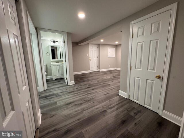 hall featuring dark wood-style floors, baseboards, and recessed lighting