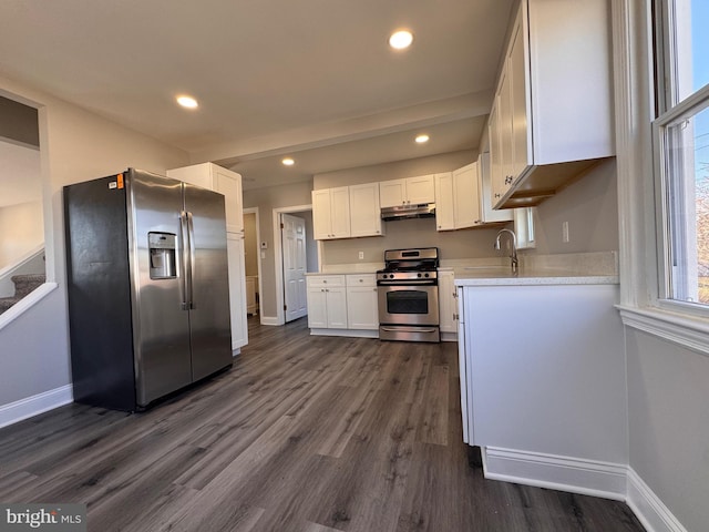 kitchen featuring light countertops, appliances with stainless steel finishes, dark wood-type flooring, white cabinets, and under cabinet range hood