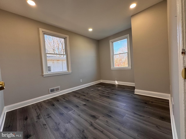 empty room featuring dark wood-style floors, recessed lighting, visible vents, and baseboards