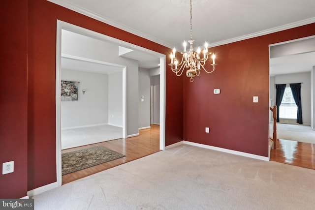 spare room with a notable chandelier, ornamental molding, wood finished floors, carpet flooring, and baseboards