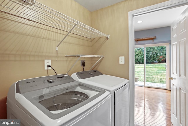 clothes washing area featuring wood-type flooring, washing machine and dryer, and laundry area