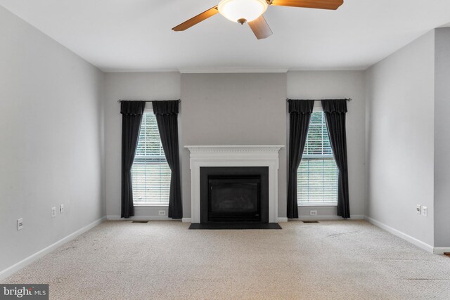 unfurnished living room with a fireplace with flush hearth, baseboards, carpet, and ceiling fan