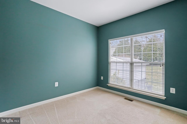 carpeted spare room with a wealth of natural light, visible vents, and baseboards