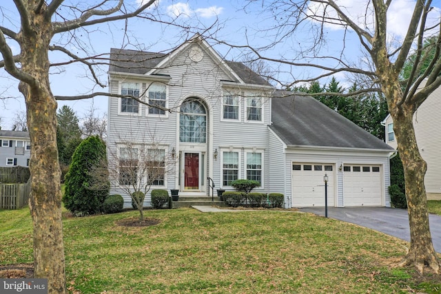 traditional-style house with a garage, a shingled roof, a front yard, and aphalt driveway