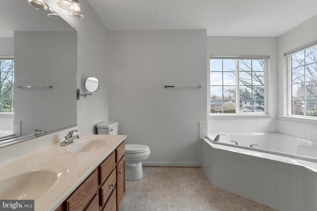 bathroom featuring a sink, a garden tub, double vanity, and toilet