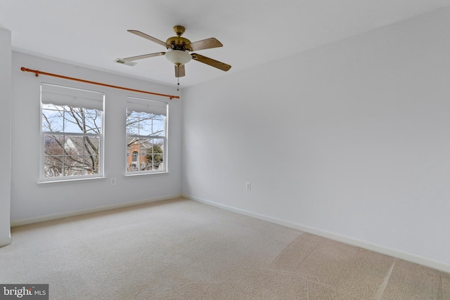 carpeted spare room with baseboards, visible vents, and ceiling fan