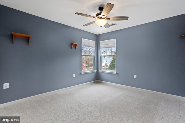 carpeted spare room featuring visible vents, baseboards, and a ceiling fan