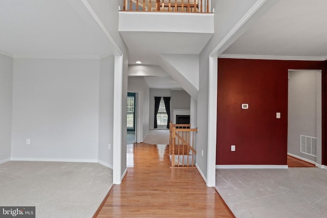 foyer entrance featuring visible vents, baseboards, ornamental molding, and light wood finished floors