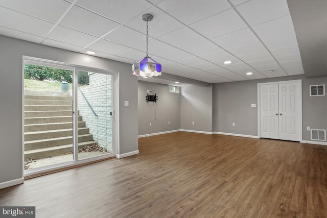 below grade area with visible vents, a paneled ceiling, wood finished floors, and stairway