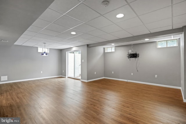 below grade area with wood finished floors, baseboards, and a healthy amount of sunlight