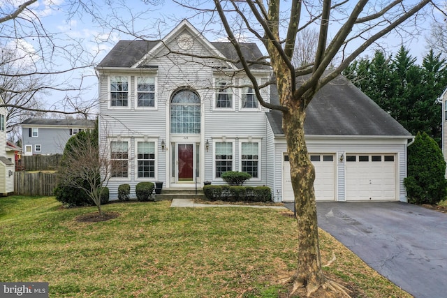 view of front facade with aphalt driveway, a garage, a front yard, and fence