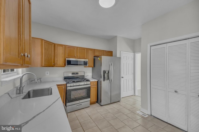 kitchen featuring visible vents, light countertops, appliances with stainless steel finishes, brown cabinetry, and a sink