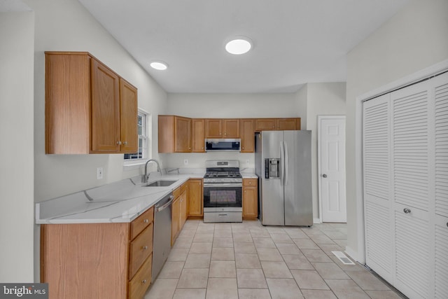 kitchen with light countertops, light tile patterned floors, appliances with stainless steel finishes, and a sink