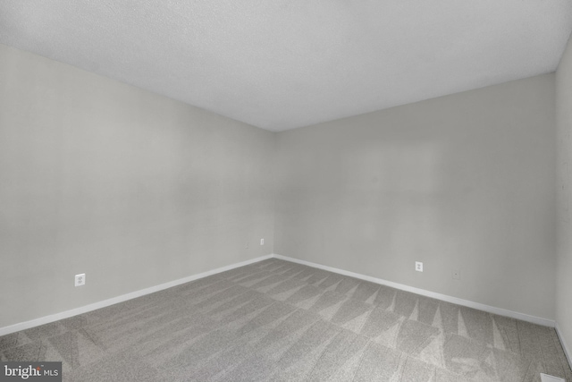 carpeted empty room featuring a textured ceiling and baseboards