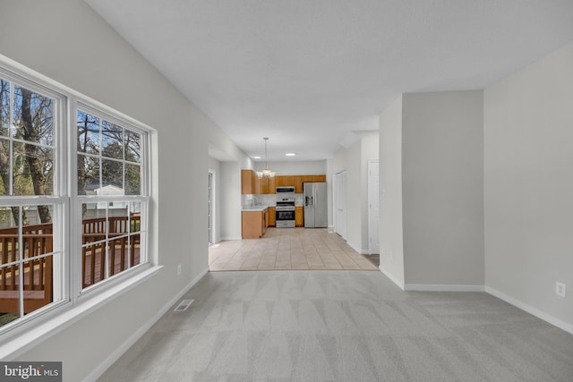 unfurnished living room featuring baseboards, visible vents, recessed lighting, light carpet, and a chandelier