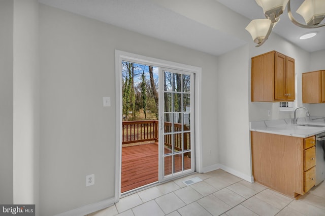 kitchen featuring visible vents, a sink, stainless steel dishwasher, light tile patterned flooring, and baseboards