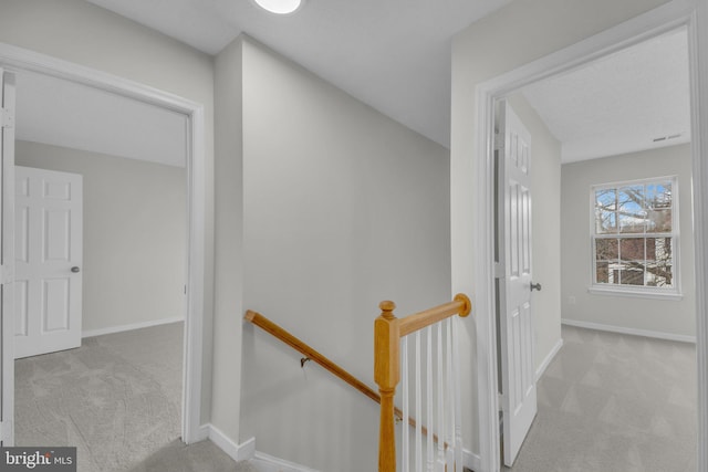 corridor with an upstairs landing, baseboards, and carpet floors