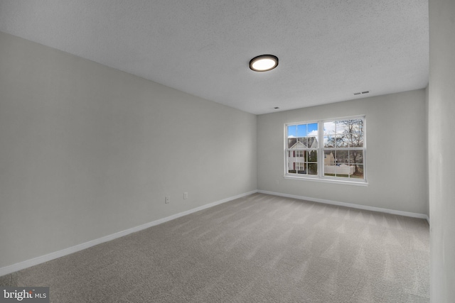 carpeted empty room with visible vents, a textured ceiling, and baseboards