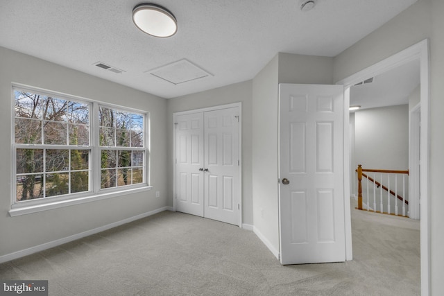 unfurnished bedroom featuring attic access, carpet flooring, baseboards, and visible vents