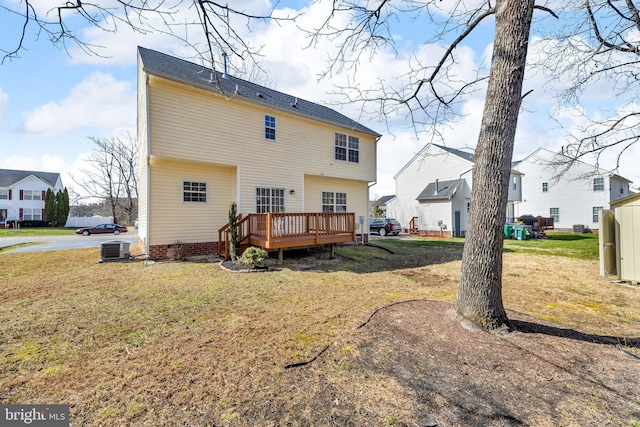 rear view of house with a deck, central AC unit, and a lawn