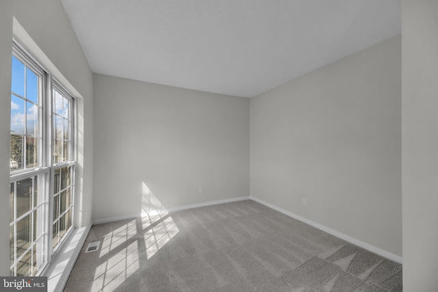 carpeted spare room with visible vents and baseboards