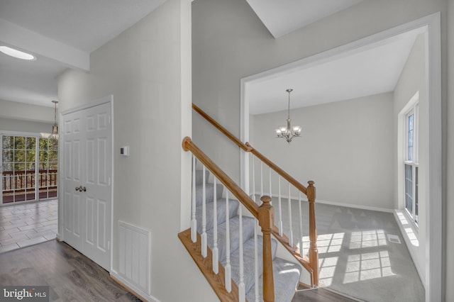 stairway with visible vents, baseboards, an inviting chandelier, and wood finished floors