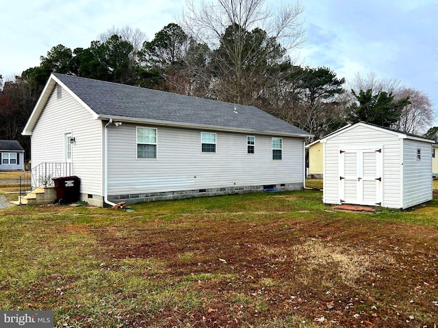 back of property featuring crawl space, a storage unit, a yard, and an outdoor structure