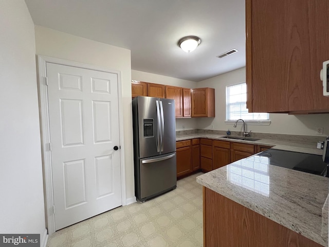 kitchen with light floors, visible vents, a sink, stainless steel refrigerator with ice dispenser, and brown cabinets