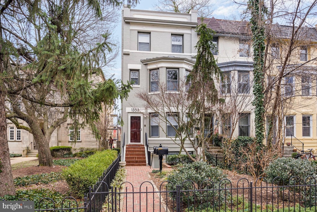 multi unit property featuring a fenced front yard, a gate, and brick siding