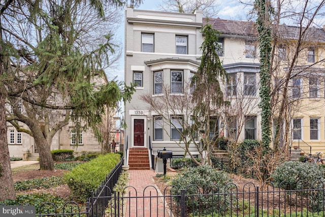 townhome / multi-family property with a fenced front yard, brick siding, and a gate