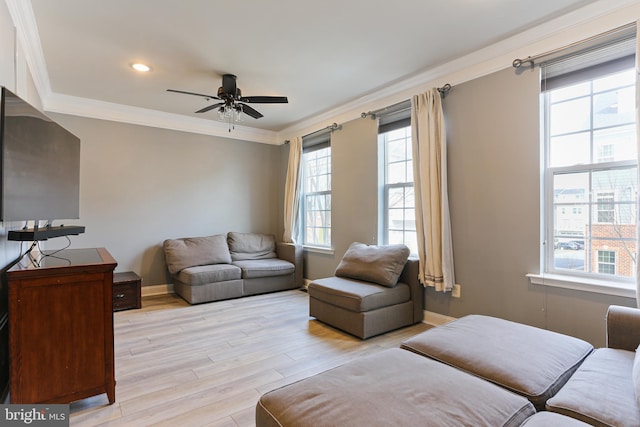 living room with crown molding, a ceiling fan, baseboards, and light wood finished floors