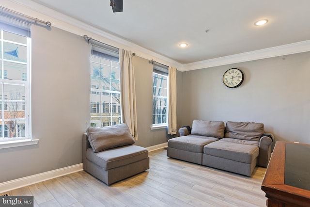 living area featuring crown molding, light wood-style flooring, and baseboards