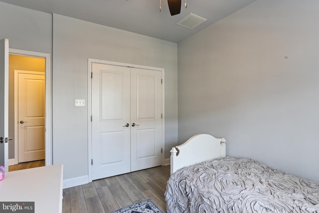 bedroom featuring visible vents, ceiling fan, baseboards, wood finished floors, and a closet