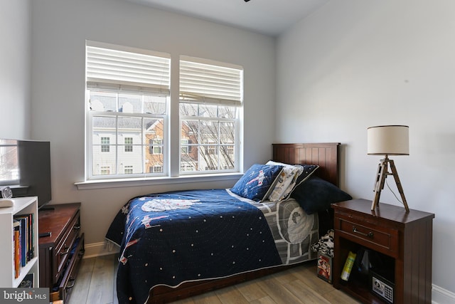 bedroom with multiple windows, baseboards, and hardwood / wood-style flooring