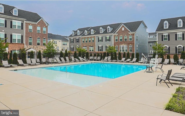 pool with a residential view, a patio, and fence