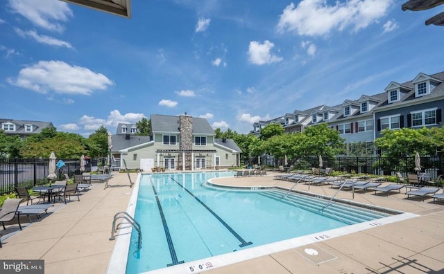 community pool with a patio area and fence