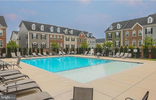 community pool featuring a patio, fence, and a residential view