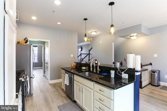 kitchen featuring a center island with sink, light wood-style flooring, a sink, white cabinets, and appliances with stainless steel finishes