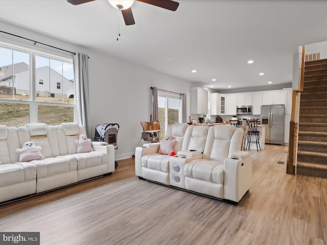 living area with visible vents, recessed lighting, light wood finished floors, ceiling fan, and stairs