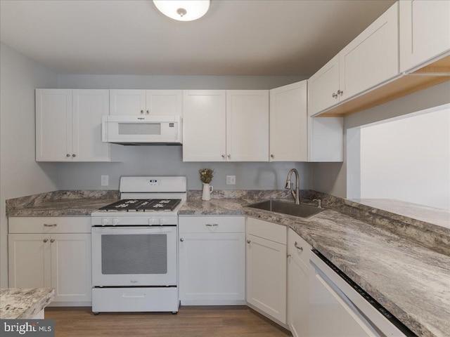 kitchen with light stone counters, light wood finished floors, white cabinets, a sink, and white appliances