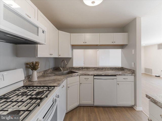 kitchen with visible vents, light wood-style floors, white cabinets, a sink, and white appliances