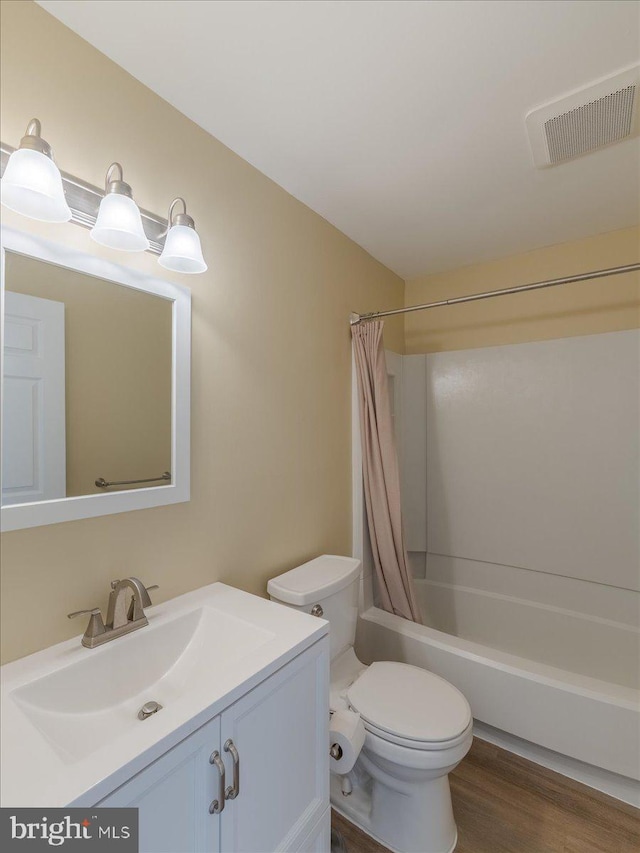 full bathroom featuring toilet, wood finished floors, vanity, visible vents, and shower / bath combo with shower curtain